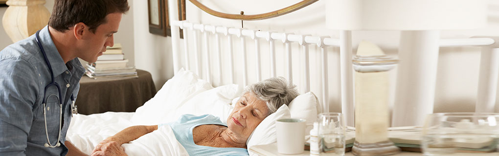 Doctor Staring at Sleeping Elderly Woman - Lead Image for Hospice Page