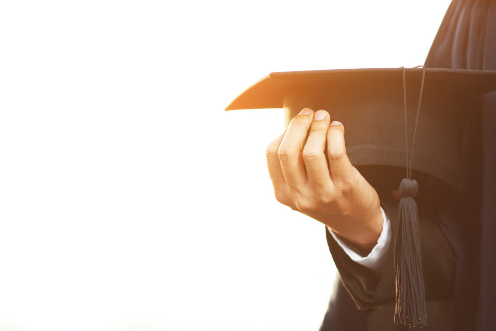 Hand holding a graduation cap, symbolizing career achievement and professional development