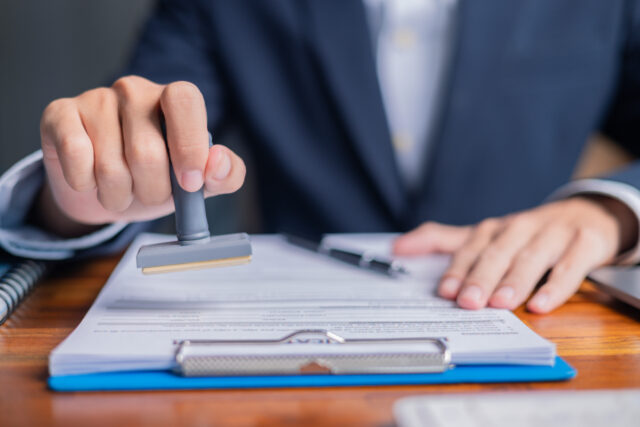 Business owner holding a stamped license document, representing compliance with licensing requirements.